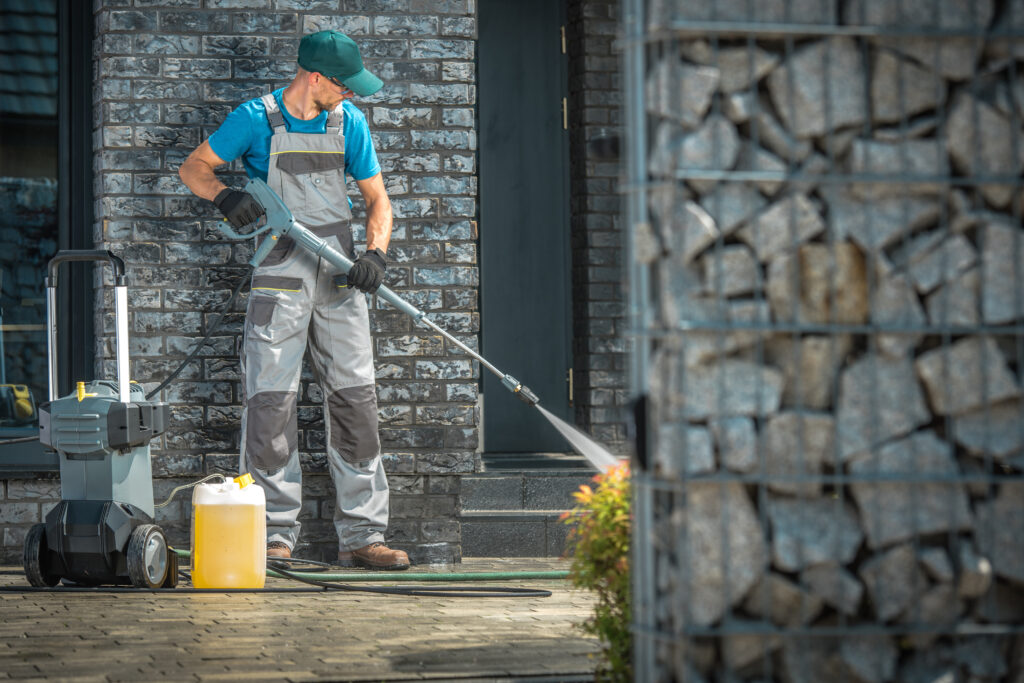 cleaning a patio with a pressure washer at a house